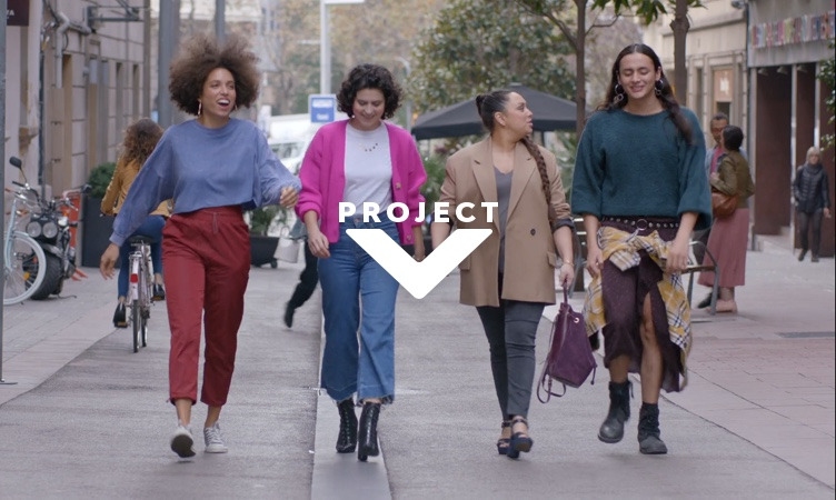 Quattro giovani donne camminano lungo la strada con il logo di PROJECT V in sovrapposizione
